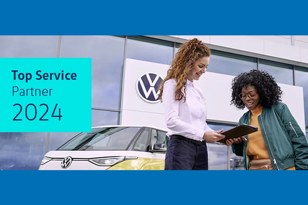 Das Bild zeigt zwei Frauen und ein VW Auto vor einem VW Autohaus