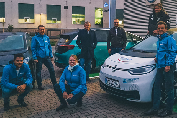 Das Bild zeigt Personen und ein E-Auto vor dem Autohaus Haitzler