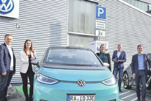 Das Bild zeigt Personen und ein E-Auto vor dem Autohaus Haitzler